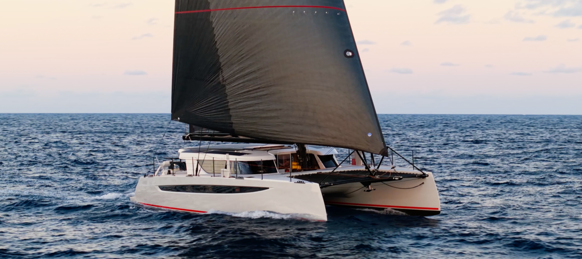 HH60 catamaran with black sails at sunset